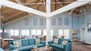 A spacious lobby with high ceilings and large windows, featuring blue sofas and a wooden coffee table. - Palm Coast, FL/Sea Colony house

 (Palm Coast)