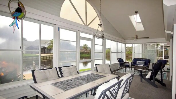 A sunroom with large windows, a dining table, and seating areas. - Palm Coast, FL/Sea Colony house

 (Palm Coast)