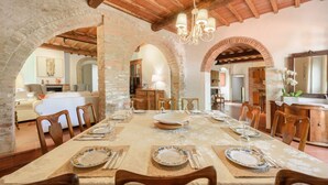 A dining area with a long table set for a meal, wooden chairs, and a chandelier. - Villa Volpaia by MMega (Barberino Tavarnelle)