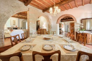 A dining area with a long table set for a meal, wooden chairs, and a chandelier.