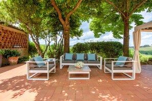 Eine Terrasse im Freien mit einer Sofagarnitur, einem Couchtisch und einer Pergola.