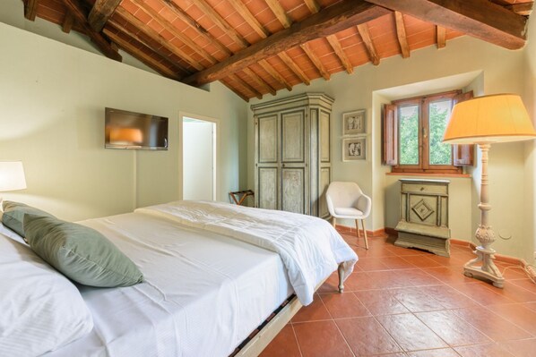 A bedroom with a bed, a chair, a cabinet, a lamp, and a window.