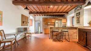 A kitchen with a wooden ceiling, a brick wall, and a bar area with stools. - Villa Volpaia by MMega (Barberino Tavarnelle)