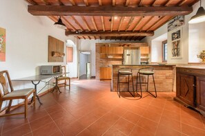 A kitchen with a wooden ceiling, a brick wall, and a bar area with stools. - Villa Volpaia by MMega (Barberino Tavarnelle)