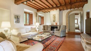 A living room with a fireplace, sofas, a coffee table, and a patterned rug. - Villa Volpaia by MMega (Barberino Tavarnelle)