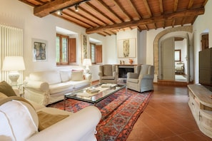 A living room with a fireplace, sofas, a coffee table, and a patterned rug. - Villa Volpaia by MMega (Barberino Tavarnelle)