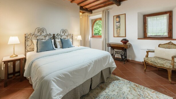 A bedroom with a bed, bedside lamps, a wooden desk, a chair, and a window with curtains. - Villa Volpaia by MMega (Barberino Tavarnelle)