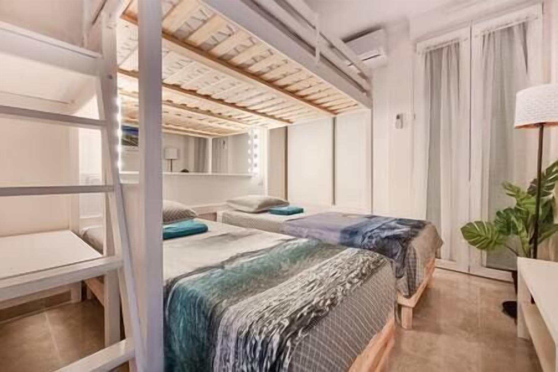 A compact hotel room with a bunk bed, a desk, and a large window with curtains.