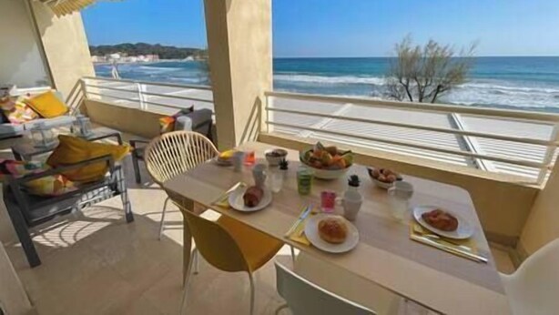 Un balcó amb taula preparat per esmorzar, amb vista al mar.