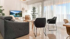 Un saló modern amb un sofà gris, un butàc negre, una taula de centre de fusta i un televisor fixat a la paret.