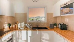 Una cuina moderna amb un gran finestral, forn integrat i taulell de fusta.
