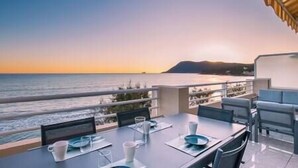 Taula preparada per dinar amb vista al mar i una muntanya a la distància.