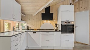 A modern kitchen with white cabinetry, a built-in oven, and a large window providing natural light. - Stunning home in Tranekær with sauna (Tranekær)