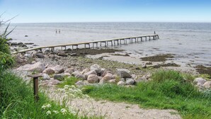 A coastal scene with a wooden pier extending into calm waters, surrounded by rocks and sparse vegetation. - Stunning home in Tranekær with sauna (Tranekær)