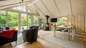 Una habitación amplia con un techo de madera grande, una chimenea y un comedor con vistas al exterior.