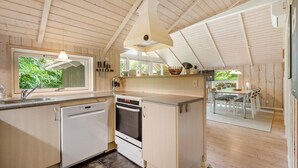 Una cocina moderna con armarios blancos, horno empotrado y una ventana grande con vistas a zonas verdes.