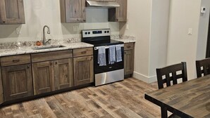 Una cocina con armarios de madera, horno de acero inoxidable y una mesa de comedor con sillas.