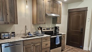 Une cuisine moderne avec des meubles en bois, des appareils électroménagers en acier inoxydable et un parquet en bois disposé en chevrons.