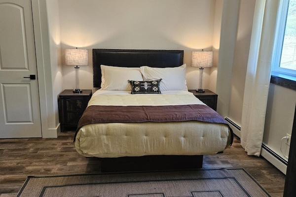 Unwind in crisp linens beneath soft, calming bedside light.