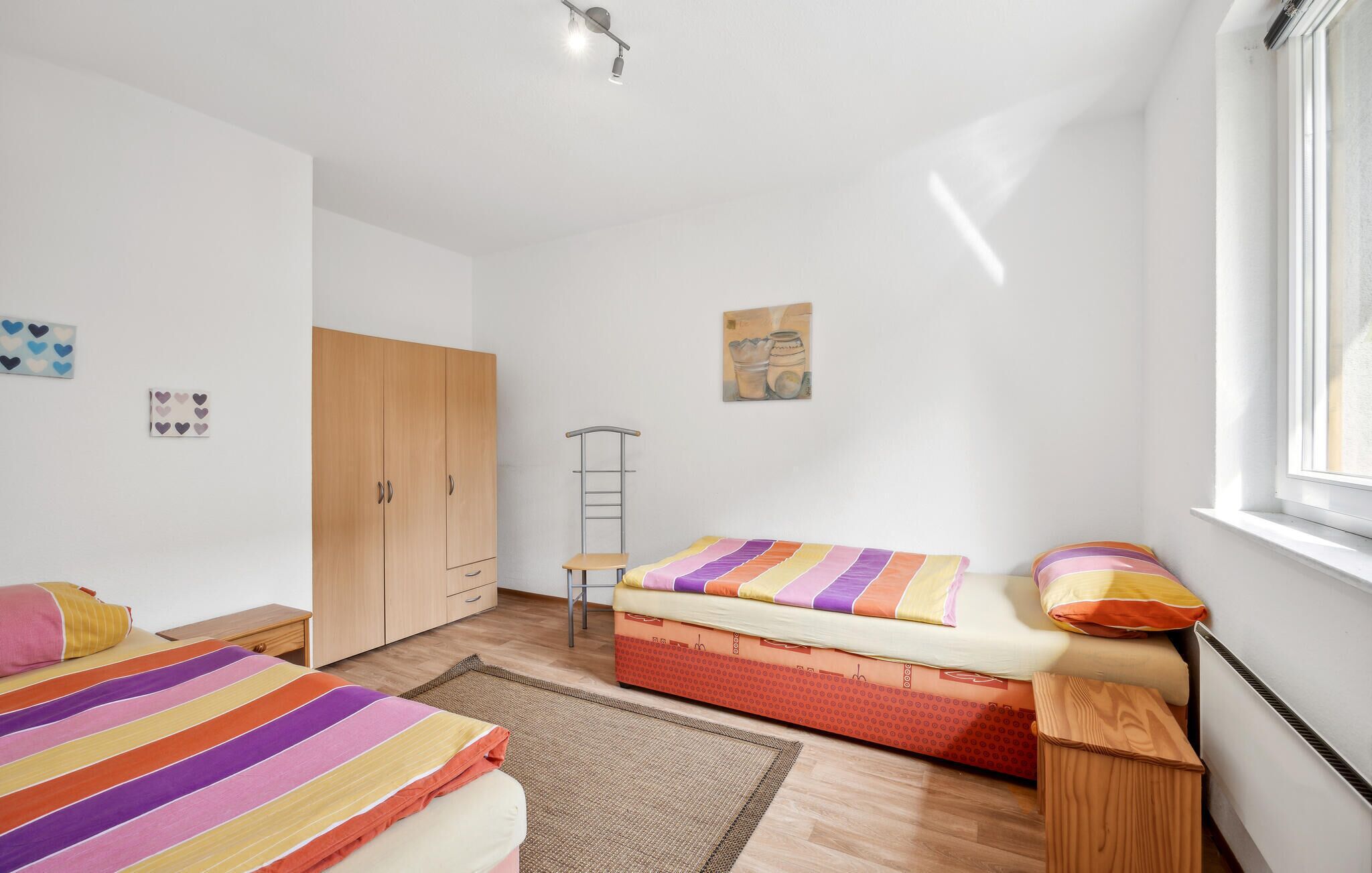 A bedroom with two beds, a wardrobe, a ladder, and a window.