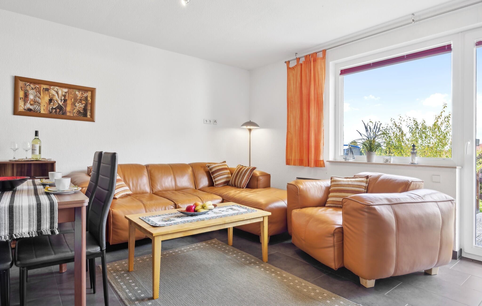A modern living room with a leather sofa set, a wooden coffee table, and a dining area with a striped table runner.