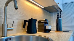 A modern kitchen with a stainless steel sink, a coffee maker, and knives on the counter. - Enchantment (Monopoli)