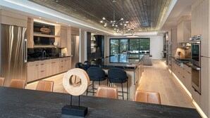 A modern kitchen with a central island, stainless steel appliances, and a dining area with leather chairs.
