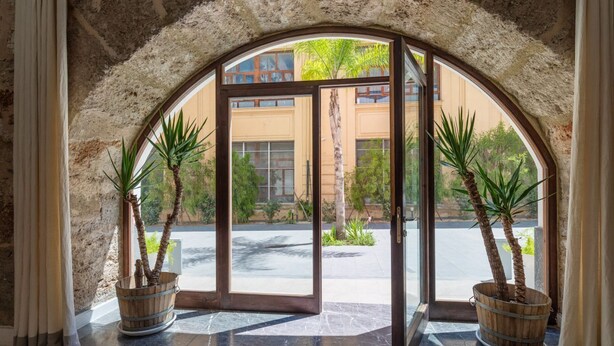 An arched doorway with a view of a building and a parking lot. - Valverde Art Space by DomuSicily (Palermo)