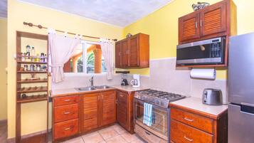 A kitchen with wooden cabinets, a gas stove, an oven, a microwave, and a refrigerator.