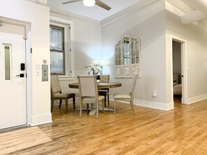 A dining area with a round table and four chairs, a decorative window, and a ceiling fan. - The Historic Lyric Presidential Suite (Cincinnati)
