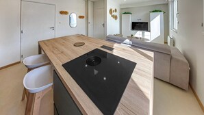 Una cocina moderna con encimera de madera, estufa integrada y zona de comedor con sofá y televisor.