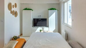 Un dormitorio moderno con cama, televisor y ventana.