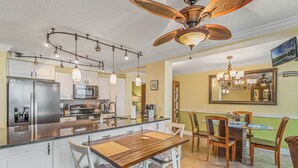 A kitchen with a central island, white cabinetry, stainless steel appliances, and a dining area with a wooden table and chairs.