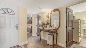 A hallway with a white door, a wooden console table with a mirror, and a small air purifier.