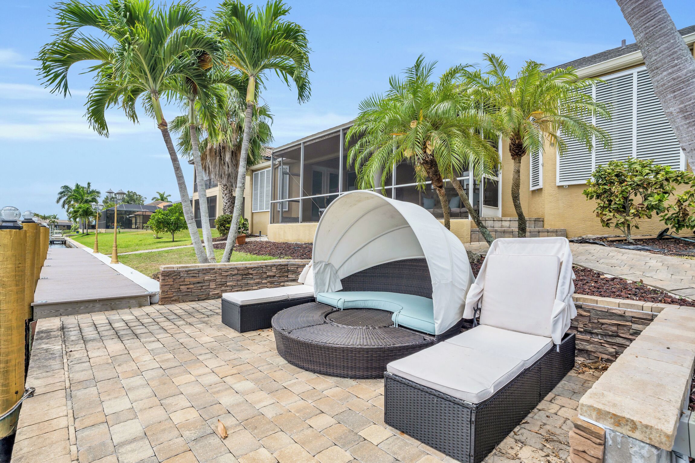 A patio with a curved seating area, a covered umbrella, and a stone pathway.