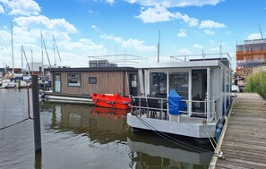 A floating houseboat docked at a marina with a small red boat nearby. - Awesome ship in Hellevoetsluis with WiFi (Hellevoetsluis)