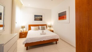 Een netjes ingerichte slaapkamer met een houten bed, nachtkastjes en twee afbeeldingen in lijsten aan de muur.