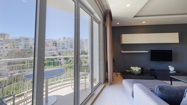 Een modern appartement met een balkon, een bank, een eettafel en een televisie.
