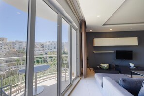 Un appartement moderne doté d’un balcon, d’un canapé, d’une table à manger et d’un téléviseur.