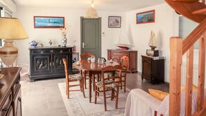 Un coin repas accueillant avec une table et des chaises en bois, un meuble contenant des objets décoratifs et un escalier menant à un autre niveau.