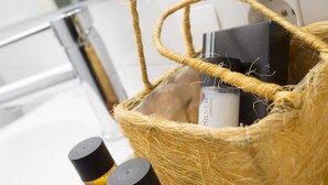Un panier en osier contenant des articles de toilette et une boîte noire avec une étiquette blanche.
