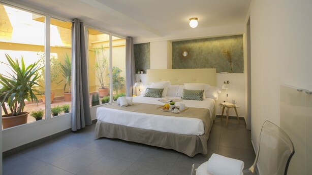 Une chambre d’hôtel moderne dotée d’un grand lit, de tables de chevet, d’un petit coin salon et offrant une vue sur l’extérieur.