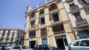 A multi-story building with various shops on the ground floor, including a pharmacy and a general store. - SingularStays Cervantes I (València)