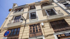 A multi-story building with balconies, a visible shop sign, and a no parking sign. - SingularStays Cervantes I (València)