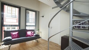 Un appartement moderne doté d’un escalier en colimaçon, d’un canapé gris avec des coussins et d’un plancher en bois.