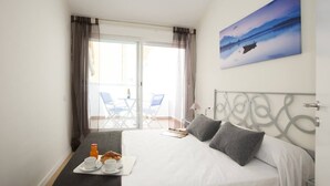 Une chambre d’hôtel avec un lit, un plateau de petit-déjeuner et un balcon équipé de chaises.