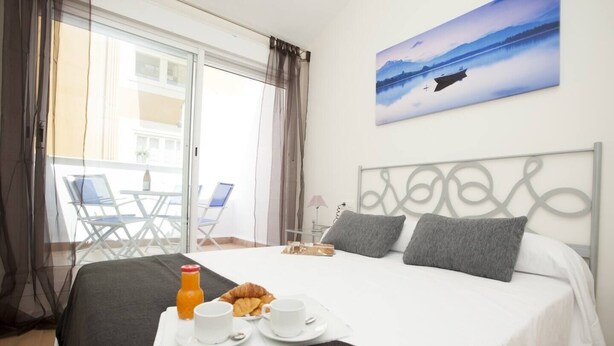 Une chambre d’hôtel avec un lit, un plateau de petit-déjeuner et un tableau représentant un bateau sur l’eau.