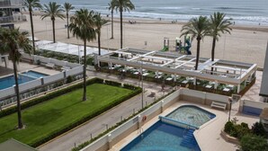 A resort with a swimming pool, beach access, and palm trees.