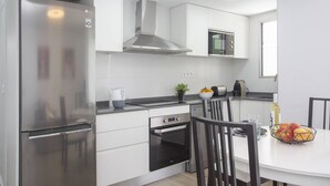 A modern kitchen with white cabinetry, stainless steel appliances, and a dining area with a table and chairs.