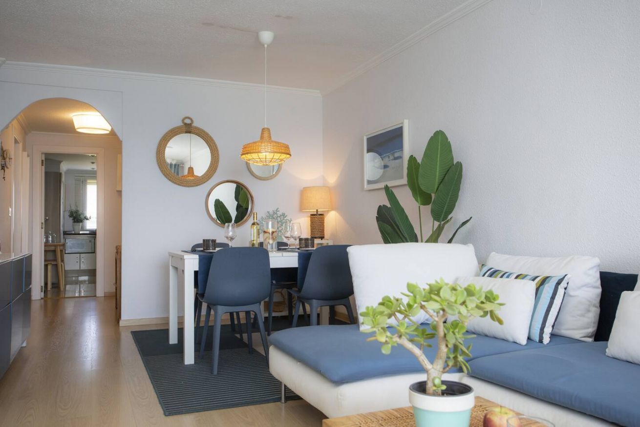 Een moderne woonkamer met een bank, eettafel, stoelen en een potplant.